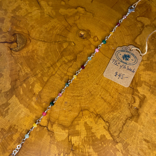 Multi colored faceted jade on Sterling Silver wire, 7 1/2 "with 1/2" Sterling heart chain extender on a wooden surface with tag
