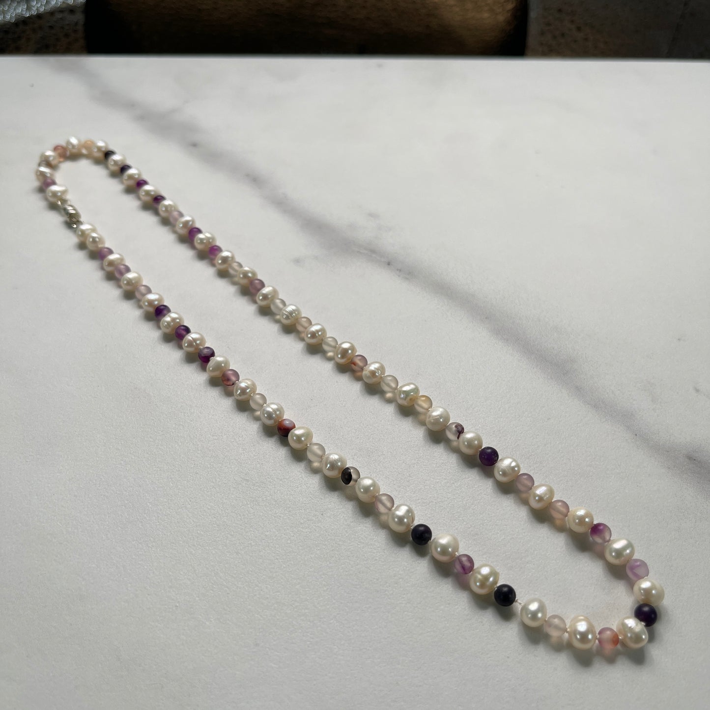 Pearl necklace with Purple jasper beads on a marble surface