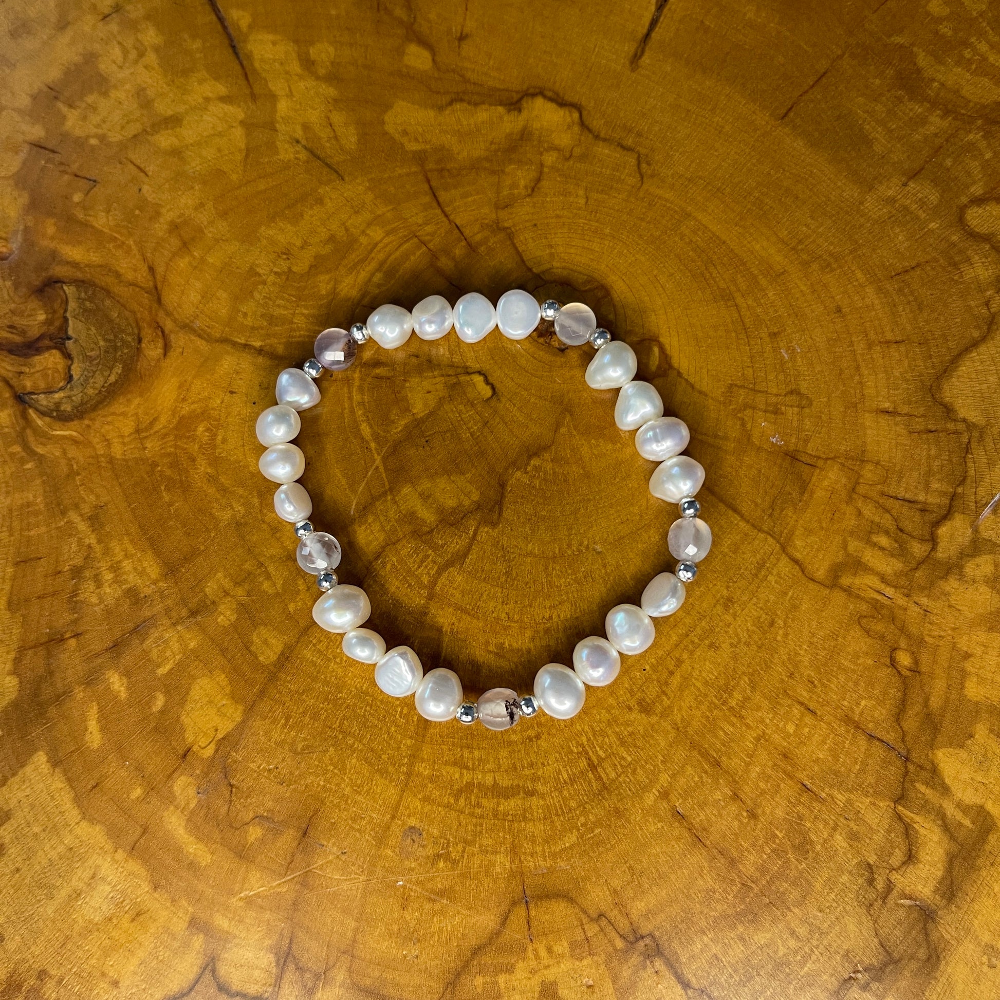 White freshwater Potato Pearls with Pink faceted Jasper on elastic, 7 1/2"on a wooden surface