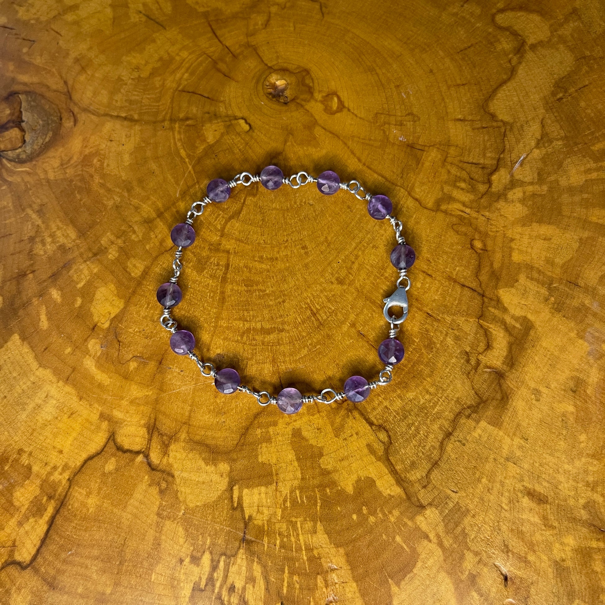 Faceted Amethyst on Sterling Silver wire with Sterling Silver Lobster clasp, 8" on wood