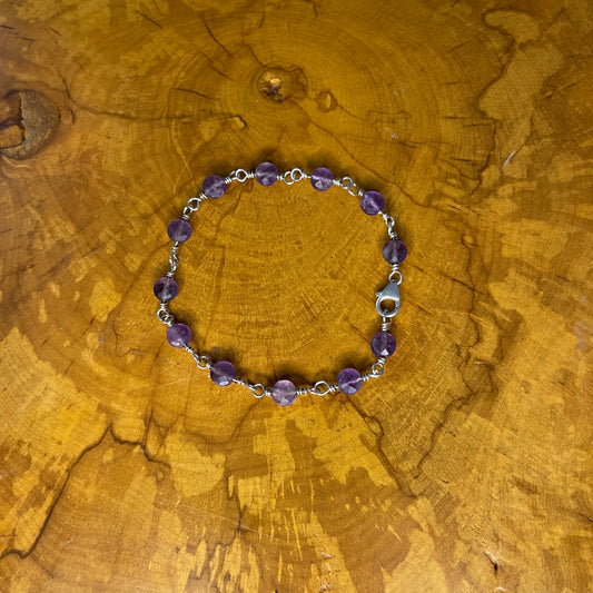 Faceted Amethyst on Sterling Silver wire with Sterling Silver Lobster clasp, 8" on wood