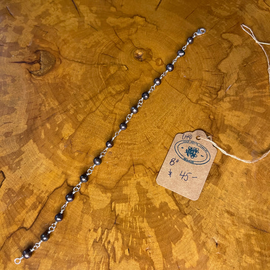 Peacock Freshwater pearls on Sterling Silver wire, 8" w/ Sterling Silver lobster clasp on wooden surface