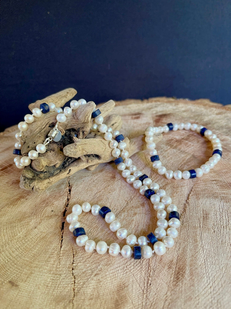 White Pearl and Lapis Lazuli heishi beaded  necklace matching stretchy bracelet on a wooden surface with a driftwood background