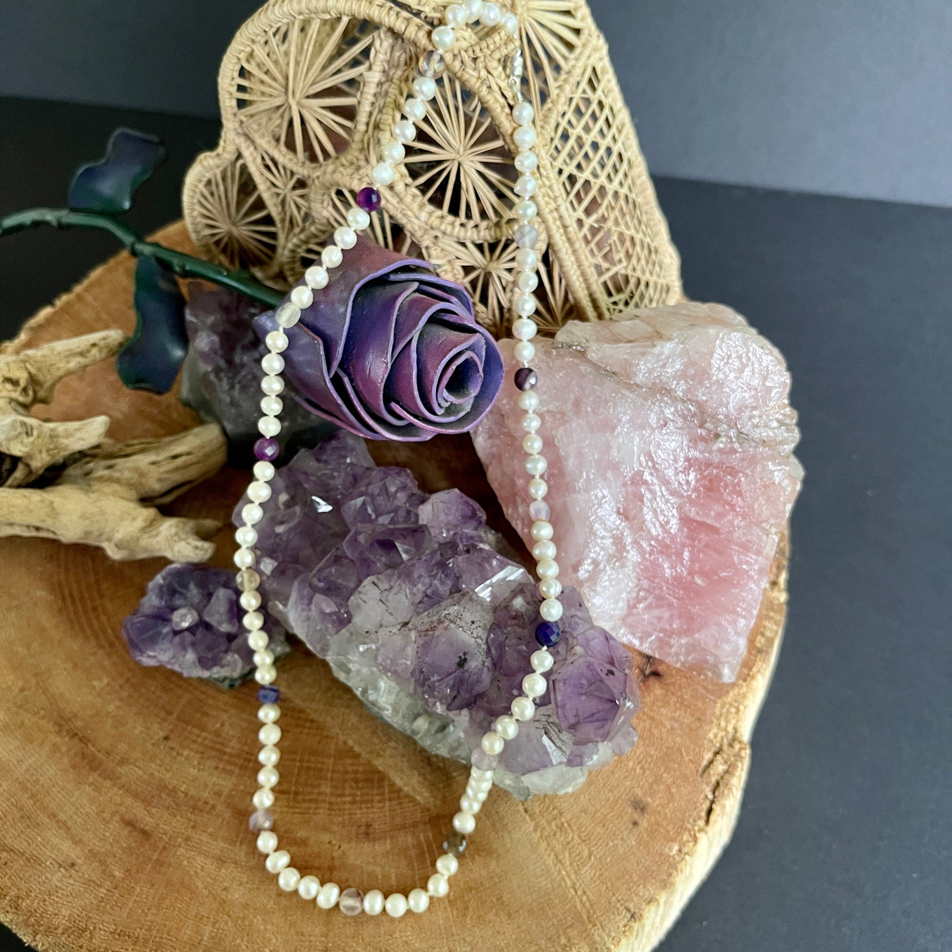 Pearl  and purple marbled jasper necklace with purple flower and crystals on a wooden surface