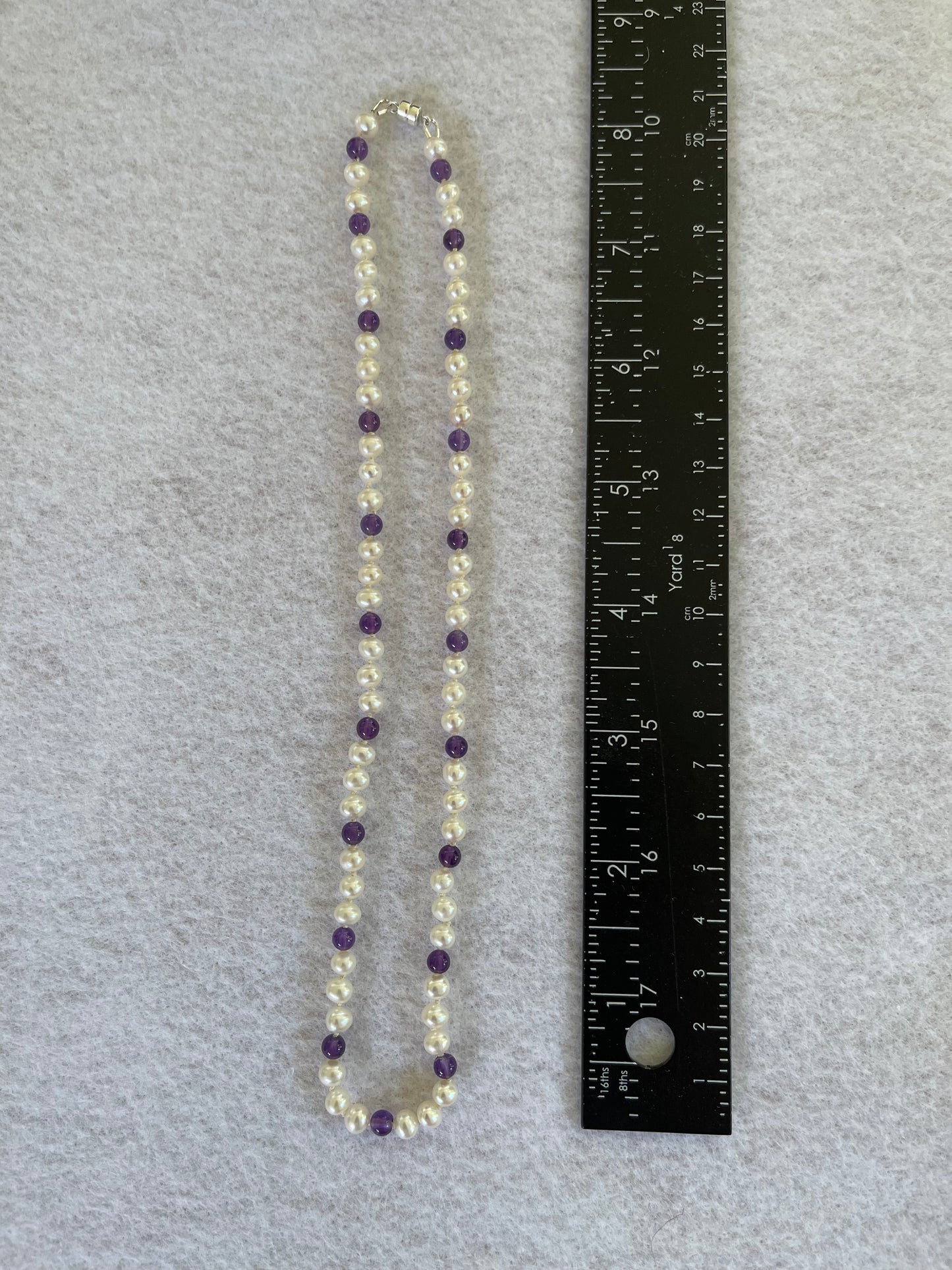 Necklace with White Pearls and Amethyst beads on a white surface with ruler