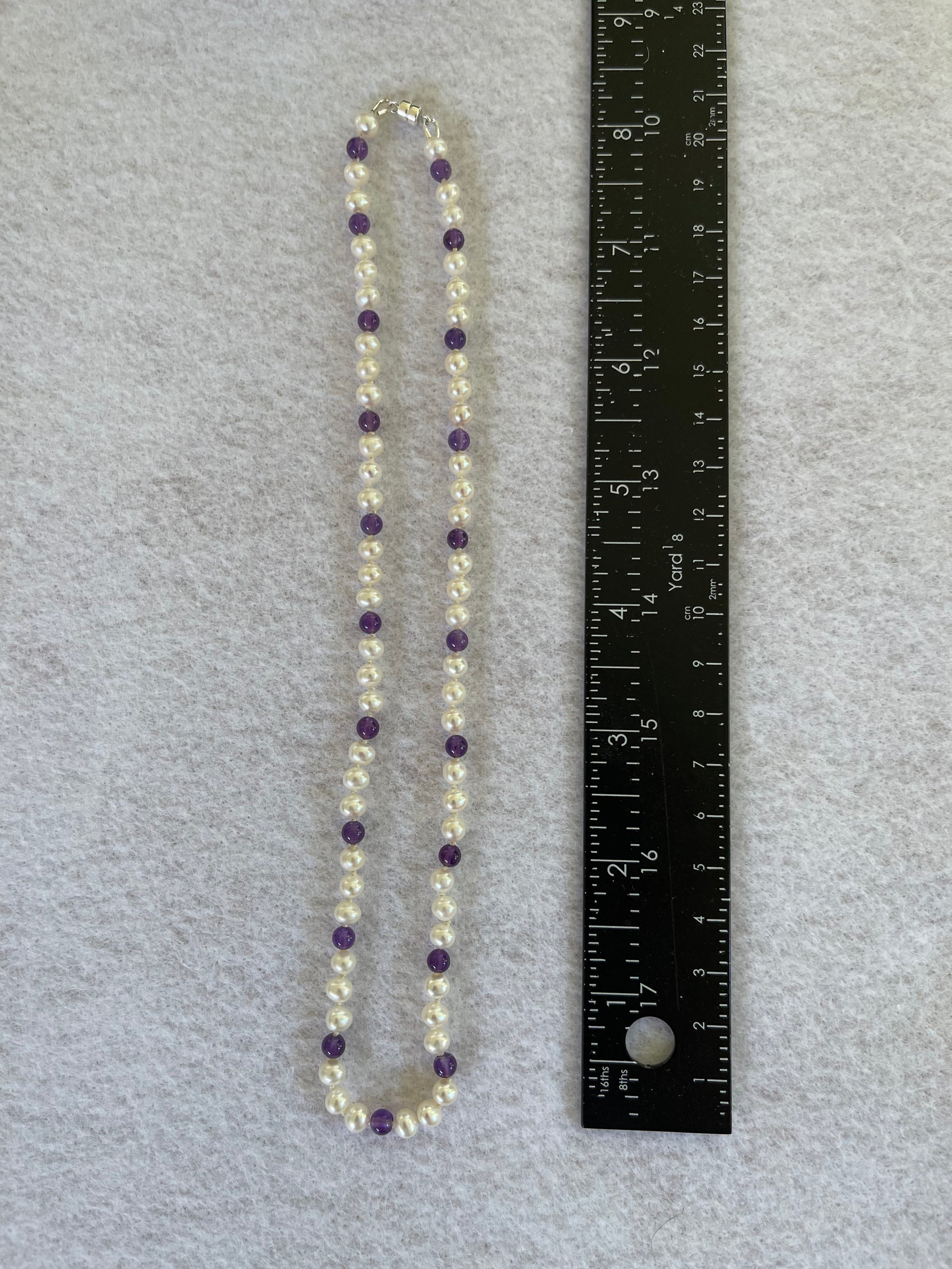 Necklace with White Pearls and Amethyst beads on a white surface with ruler