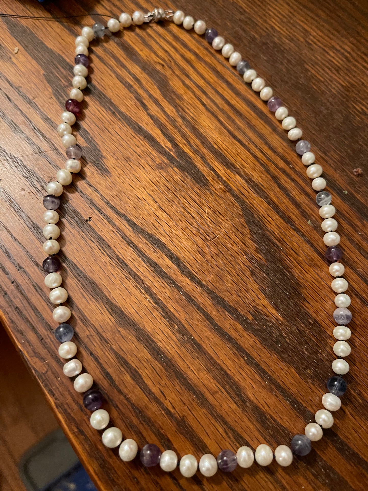 Necklace with White Pearls and Fluorite beads on a wooden surface