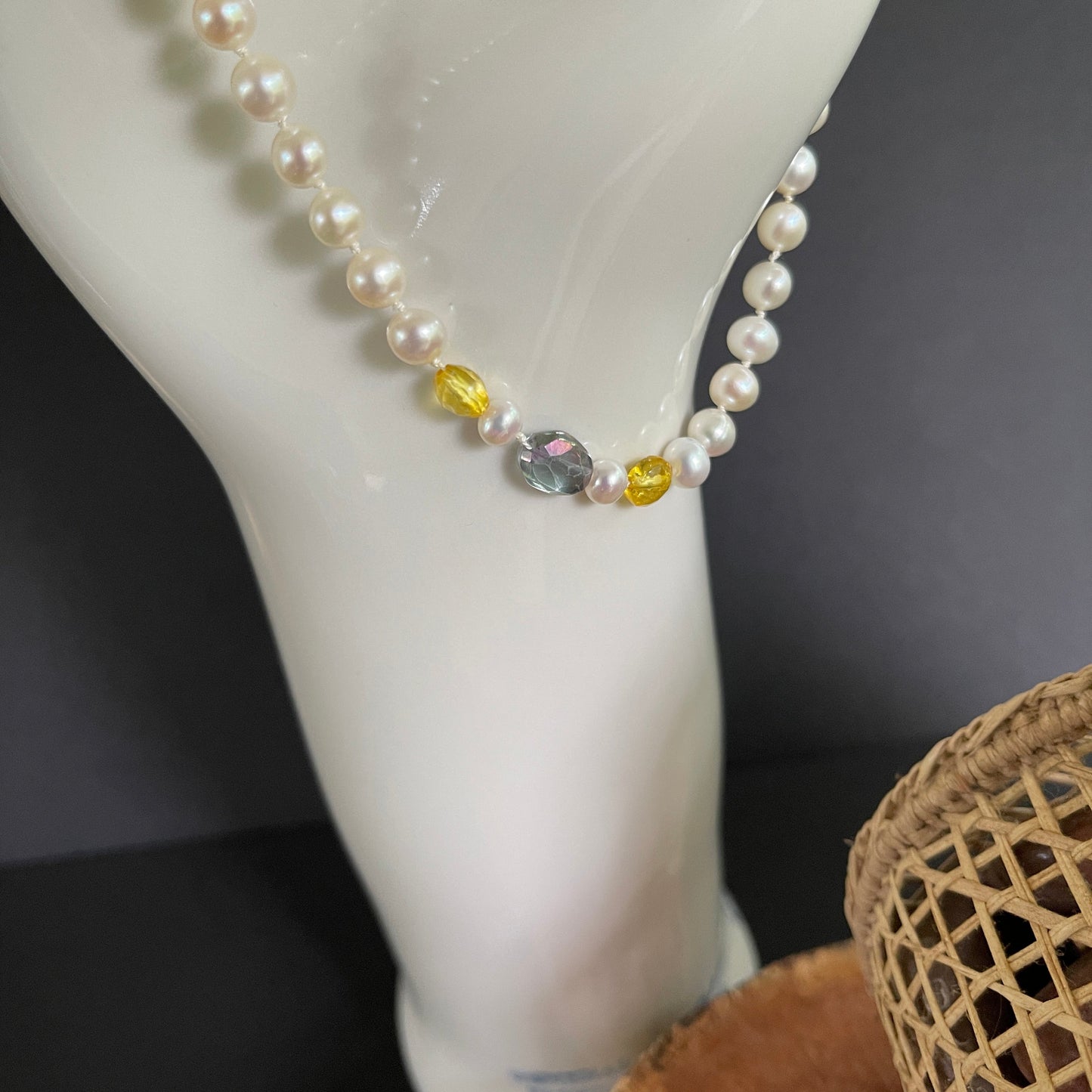 Pearl necklace with citrine and rainbow tourmaline accents on a white surface
