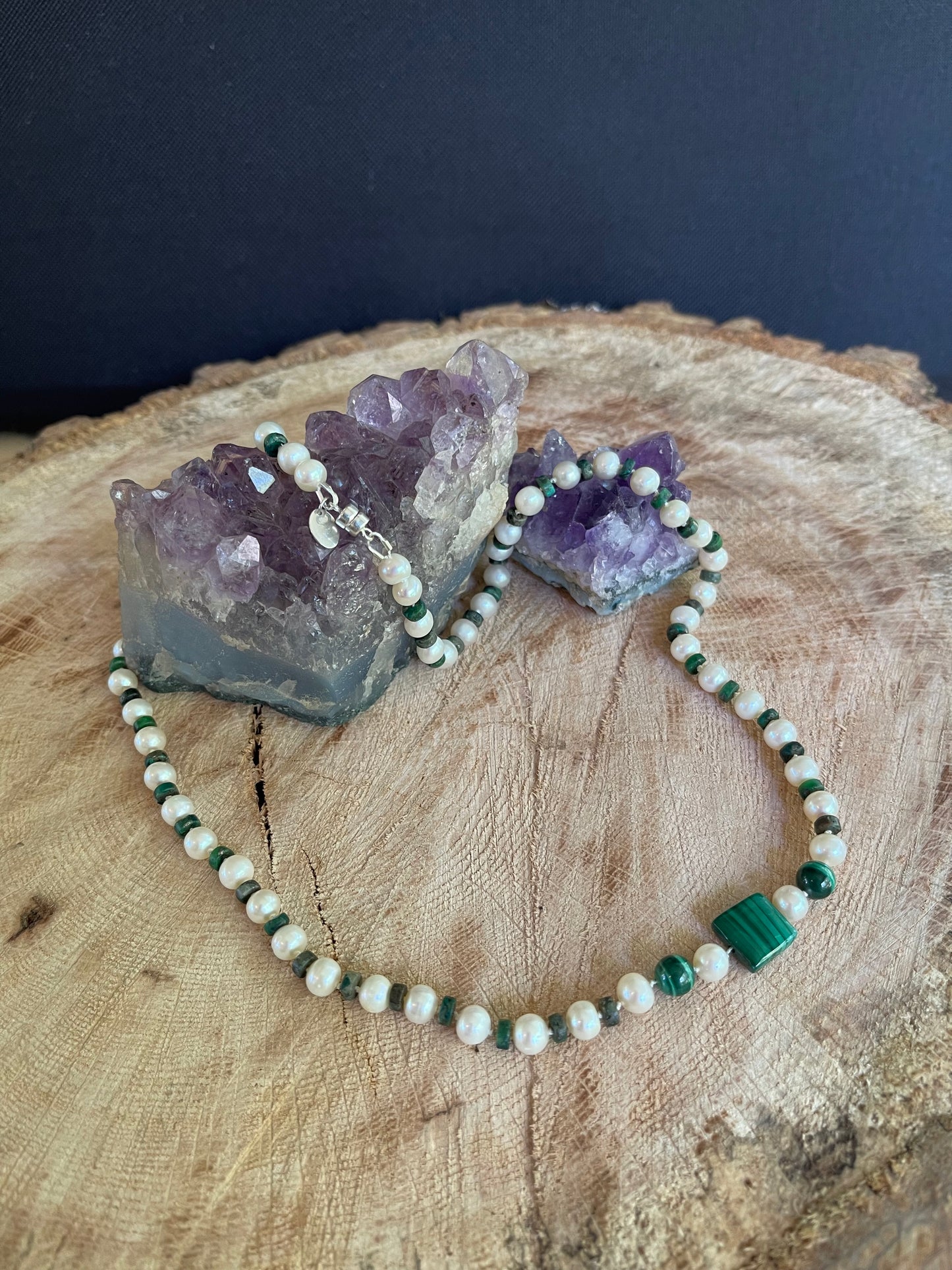 Necklace  of Malachite  and White Pearls beads on a wooden surface with natural elements
