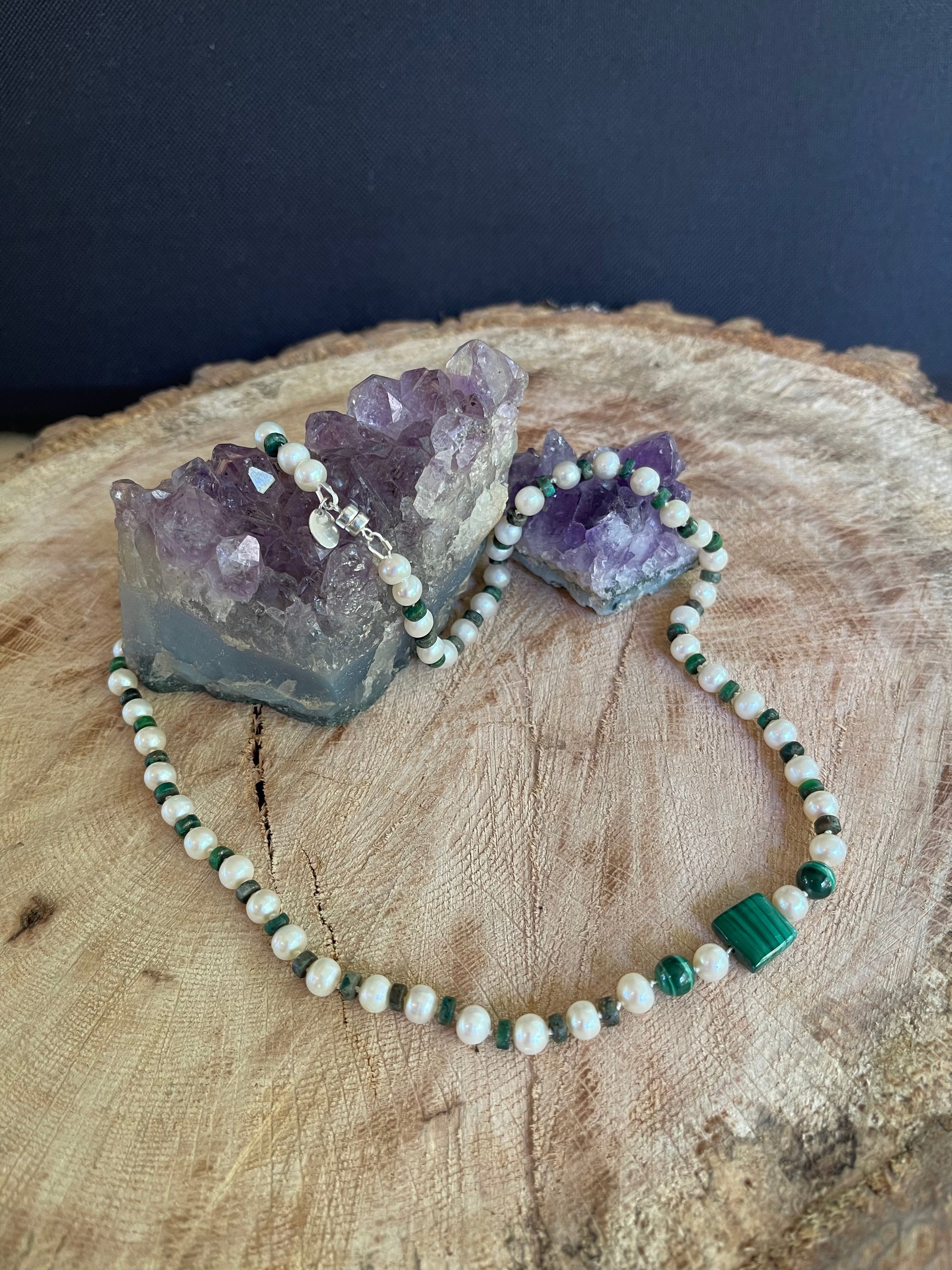 Necklace  of Malachite  and White Pearls beads on a wooden surface with natural elements