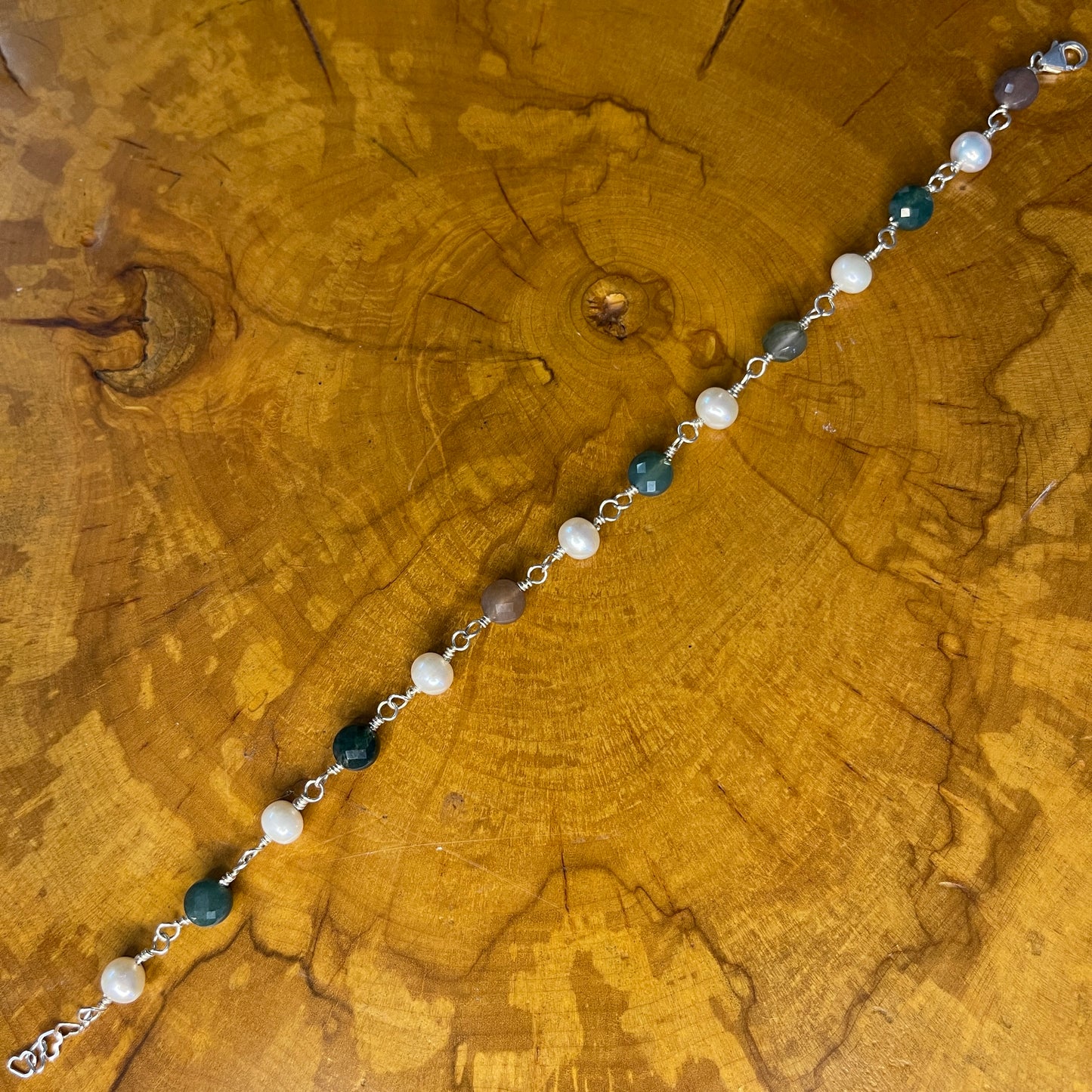 Faceted Multi colored Jasper and White Freshwater Pearls on Sterling Silver wire with Sterling Silver Lobster clasp, 8" with Sterling 1" heart chain extender on wood